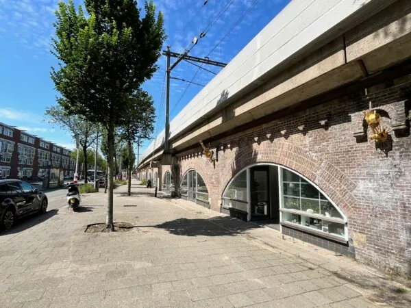 Gezicht op de winkelruimtes in de bogen onder het spoorviaduct bij ‘Tussen de Bogen’ in Amsterdam op een zonnige dag.